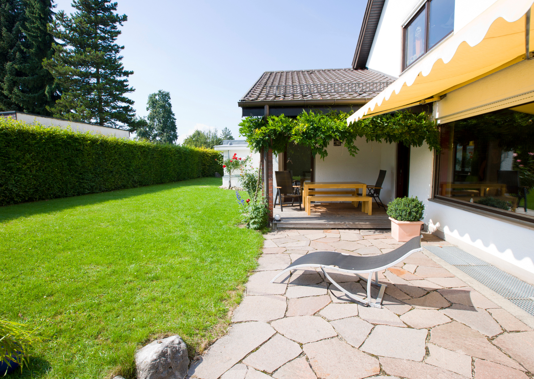 Aménagement extérieur de maison avec terrasse, allée en pierre et jardin paysager