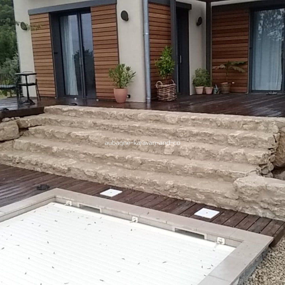 Escalier extérieur en pierre naturelle avec terrasse bois et piscine en région PACA