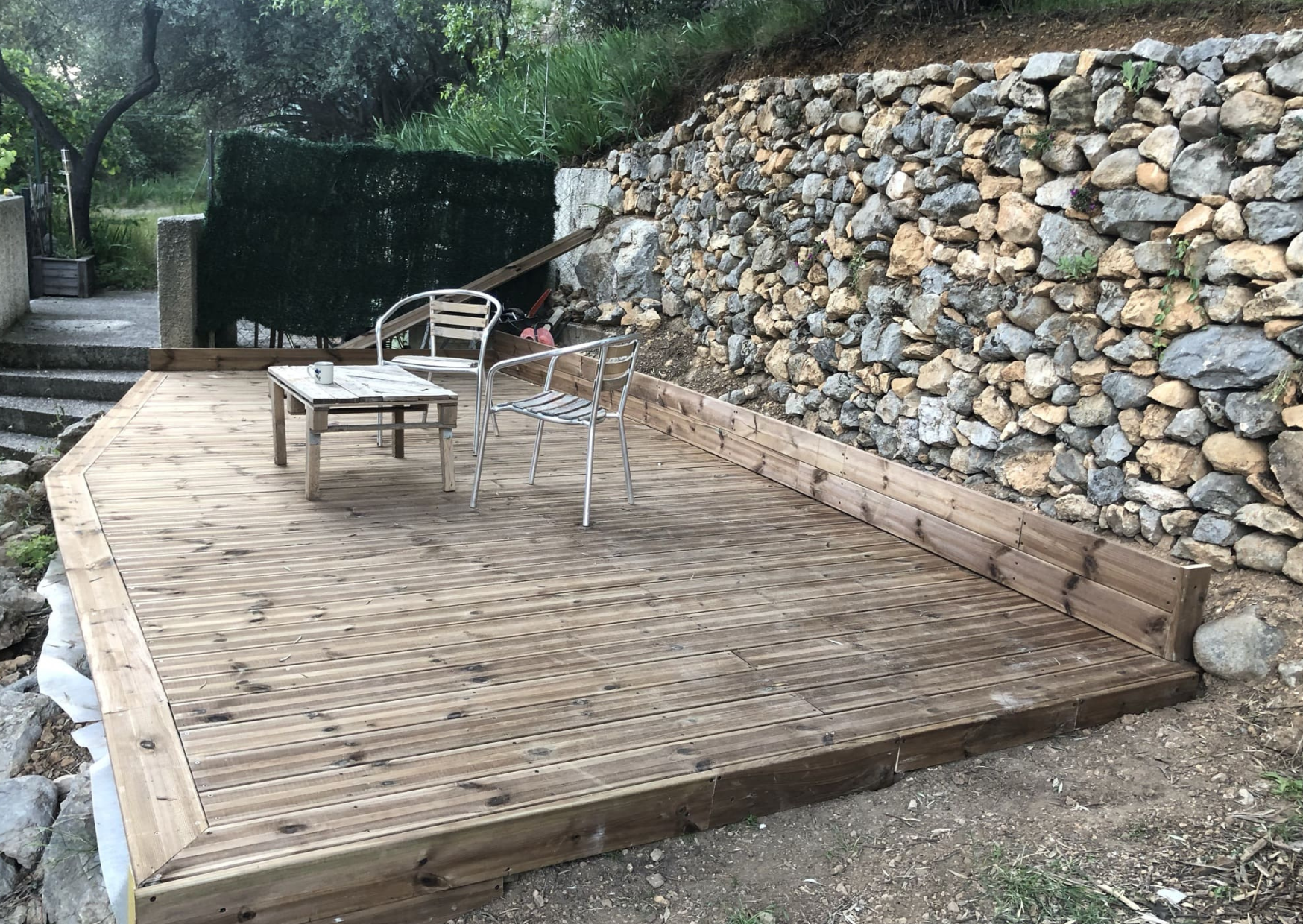 Terrasse en bois avec mur en pierre naturelle sur terrain en pente à Gémenos