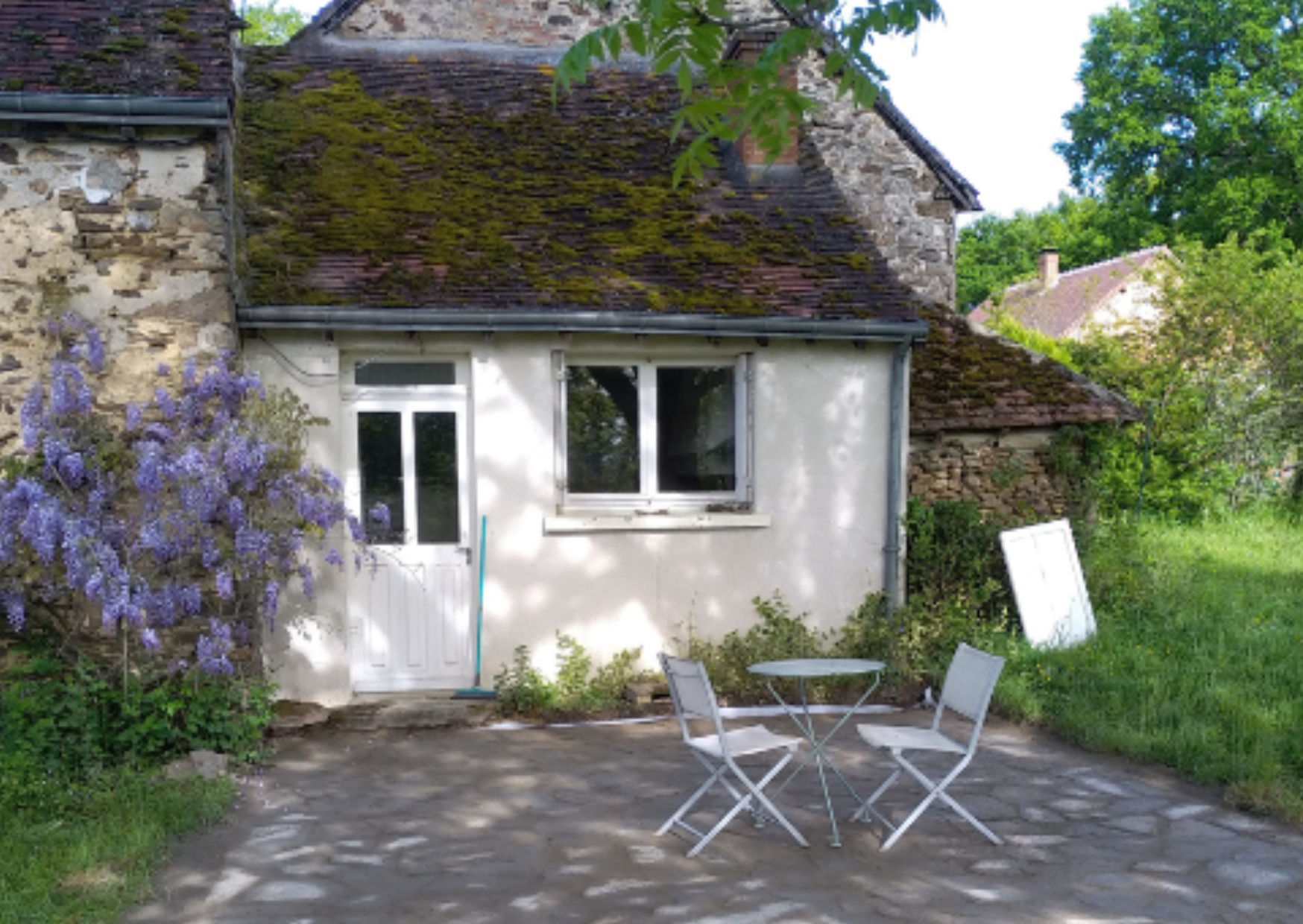 Terrasse en pierre naturelle devant une maison ancienne rénovée avec aménagement extérieur authentique